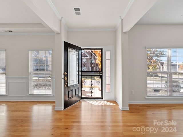 foyer entrance with crown molding and light hardwood / wood-style floors