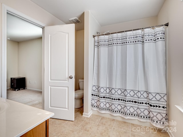 bathroom featuring toilet, walk in shower, vanity, and tile patterned floors