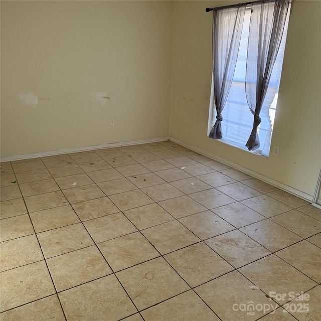 empty room with baseboards and light tile patterned floors