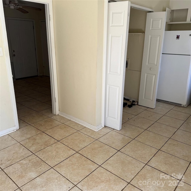 interior space featuring a ceiling fan, baseboards, and light tile patterned floors