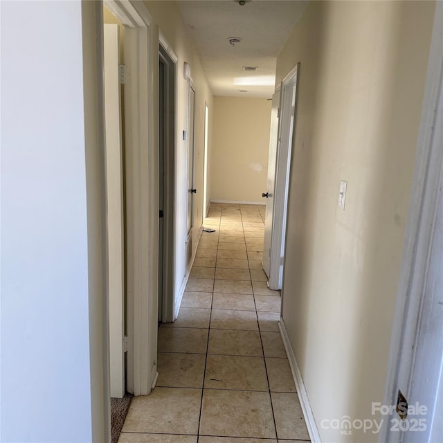 hall featuring light tile patterned floors and baseboards