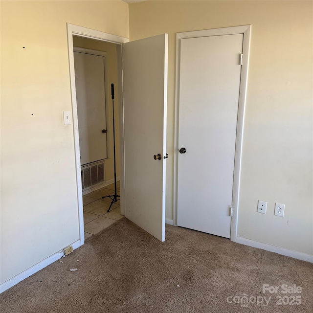 unfurnished bedroom with baseboards, visible vents, and light colored carpet