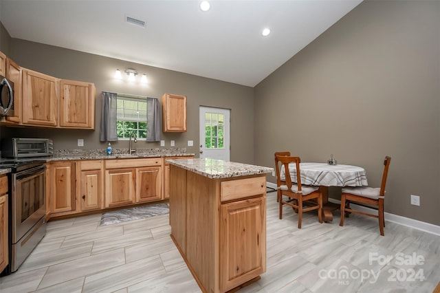 kitchen featuring light stone countertops, stainless steel appliances, sink, a kitchen island, and lofted ceiling