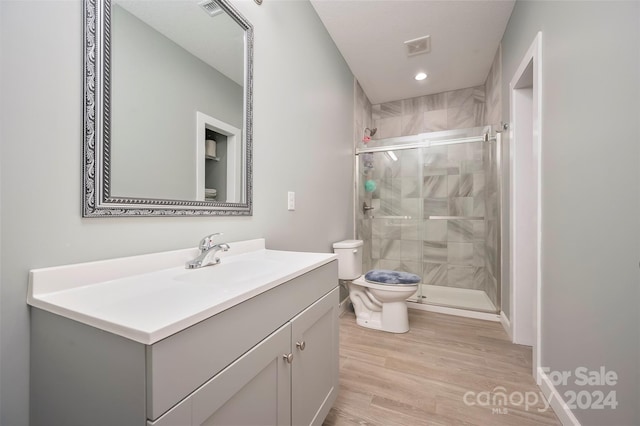 bathroom with hardwood / wood-style floors, vanity, toilet, and a shower with door