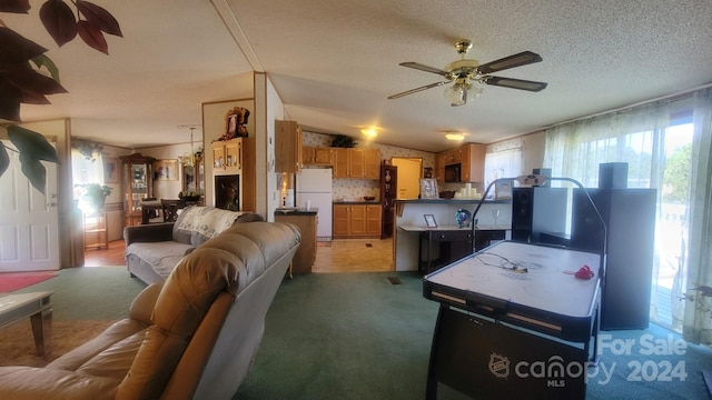 carpeted living room featuring ceiling fan, vaulted ceiling, and a textured ceiling