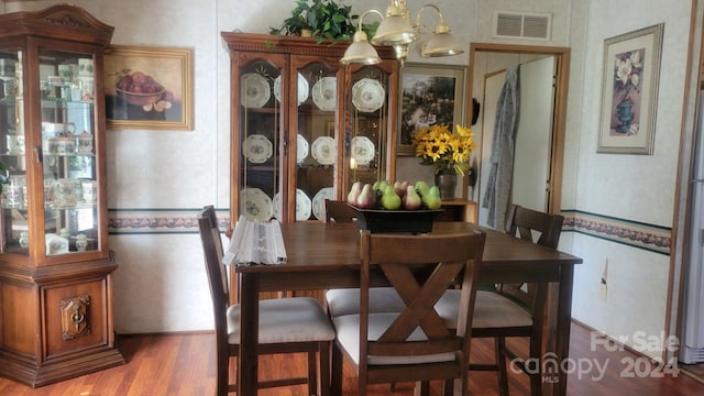 dining room featuring wood-type flooring and an inviting chandelier