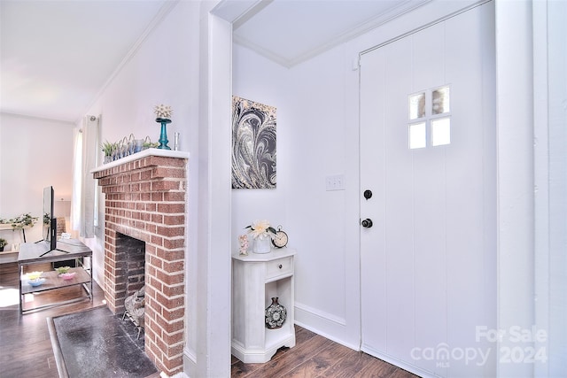 foyer entrance with ornamental molding, dark wood-type flooring, and a brick fireplace