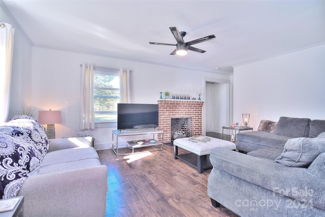 living room featuring dark wood-type flooring, ceiling fan, ornamental molding, and a brick fireplace