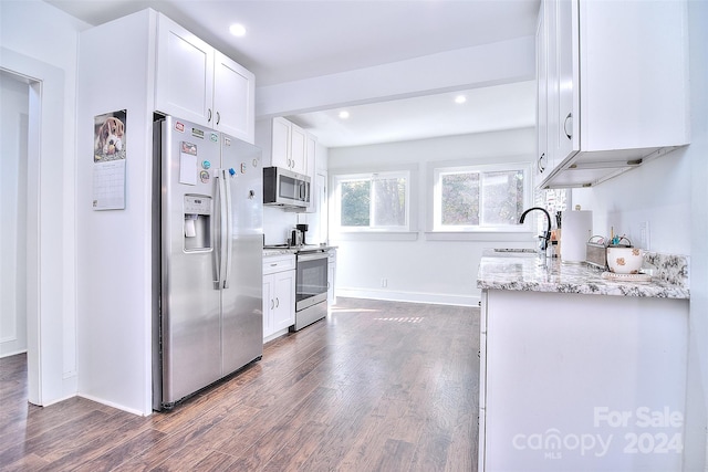 kitchen with dark wood-type flooring, stainless steel appliances, sink, white cabinetry, and light stone counters