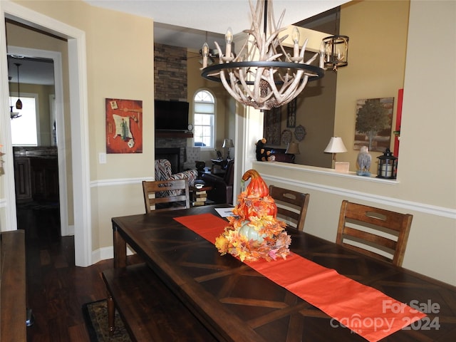 dining space featuring a chandelier, a stone fireplace, and hardwood / wood-style flooring