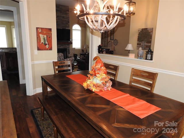 dining room with an inviting chandelier, dark wood-type flooring, and a fireplace