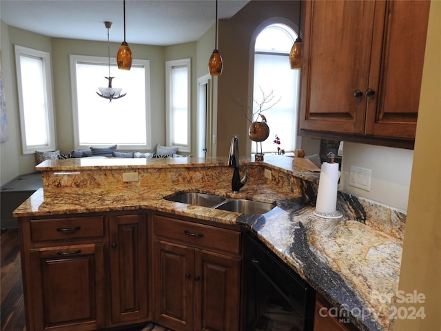 kitchen featuring dishwasher, kitchen peninsula, sink, decorative light fixtures, and light stone counters