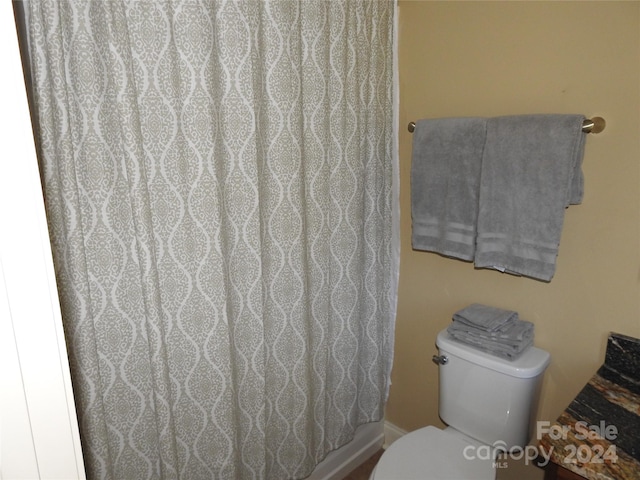 bathroom featuring toilet and curtained shower