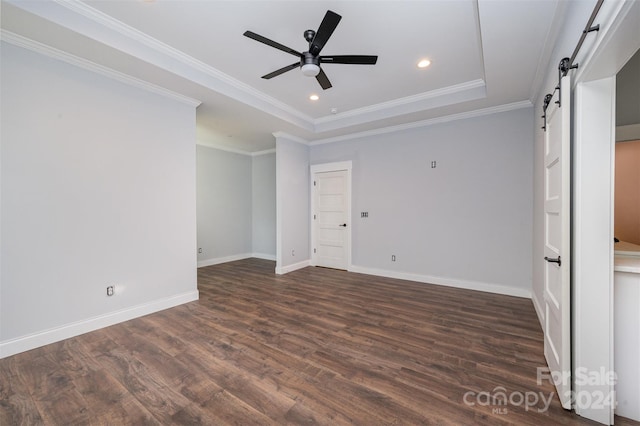 empty room with ornamental molding, a barn door, dark hardwood / wood-style floors, and ceiling fan