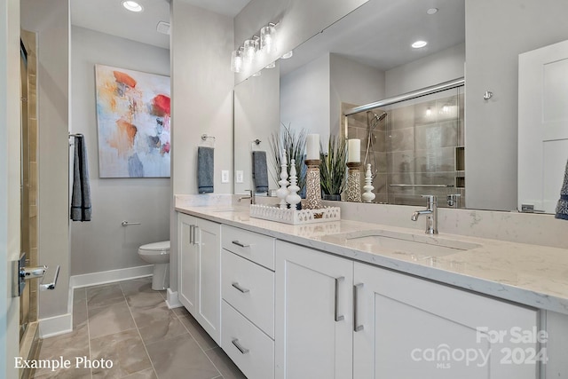 bathroom featuring vanity, a shower with shower door, and toilet