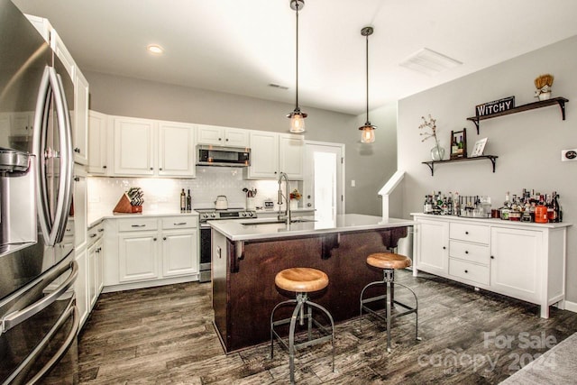 kitchen with a center island with sink, white cabinetry, dark wood-type flooring, pendant lighting, and stainless steel appliances