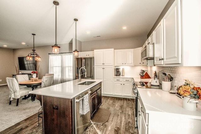 kitchen with a center island with sink, white cabinetry, stainless steel appliances, decorative light fixtures, and dark hardwood / wood-style floors