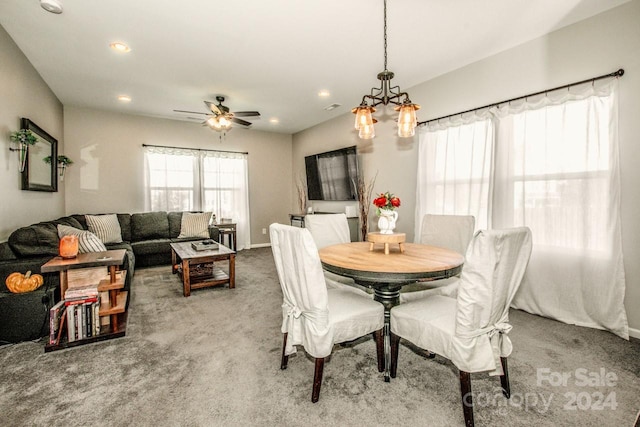 carpeted dining space featuring ceiling fan with notable chandelier