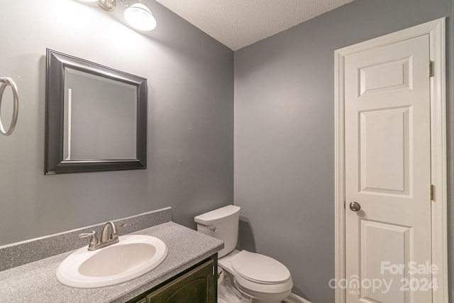 bathroom with a textured ceiling, vanity, and toilet