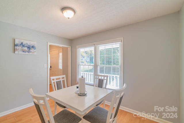 dining space featuring light wood-type flooring and a textured ceiling