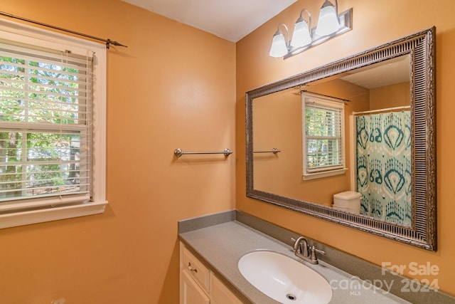 bathroom featuring toilet, plenty of natural light, vanity, and a shower with shower curtain