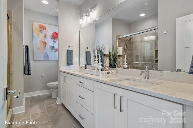 bathroom featuring baseboards, toilet, a sink, a shower stall, and double vanity