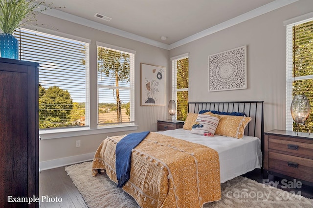 bedroom with ornamental molding, baseboards, visible vents, and wood finished floors