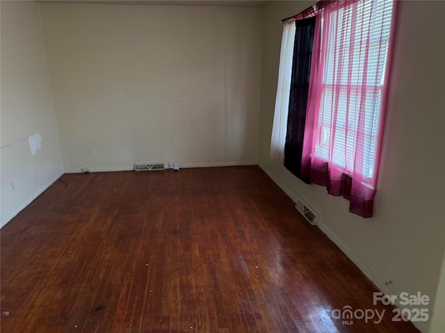 spare room featuring visible vents and dark wood-style flooring