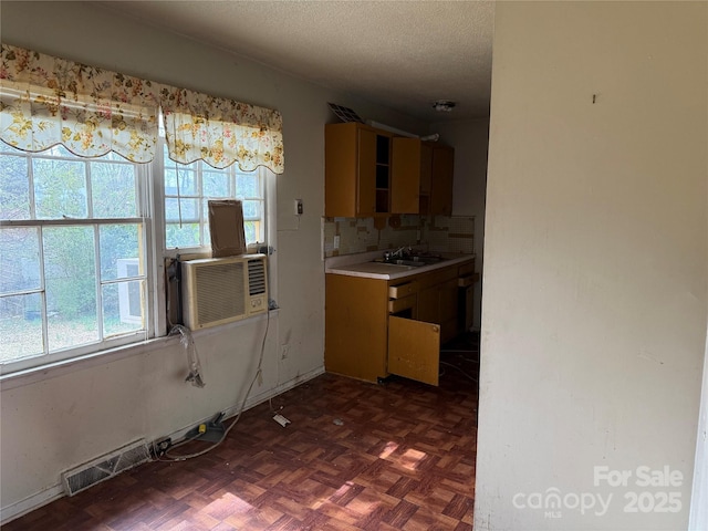 kitchen with visible vents, backsplash, light countertops, a textured ceiling, and a sink