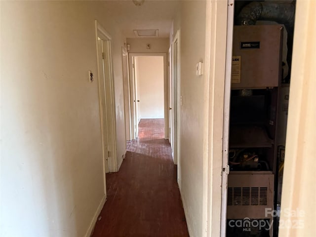 corridor with dark wood-style flooring, attic access, and baseboards