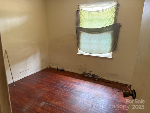 empty room with hardwood / wood-style flooring and baseboards