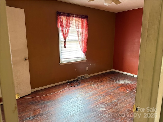 spare room featuring hardwood / wood-style flooring, ceiling fan, visible vents, and baseboards