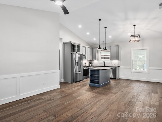 kitchen with gray cabinetry, pendant lighting, vaulted ceiling, a kitchen island, and stainless steel appliances