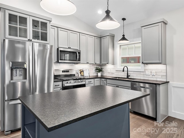 kitchen featuring sink, a center island, tasteful backsplash, vaulted ceiling, and appliances with stainless steel finishes