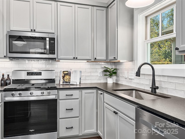 kitchen featuring decorative backsplash, appliances with stainless steel finishes, white cabinets, and sink