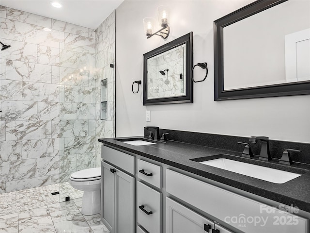 bathroom with a tile shower, vanity, and toilet