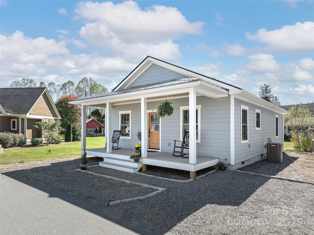 bungalow-style home featuring covered porch, central AC unit, and a front yard