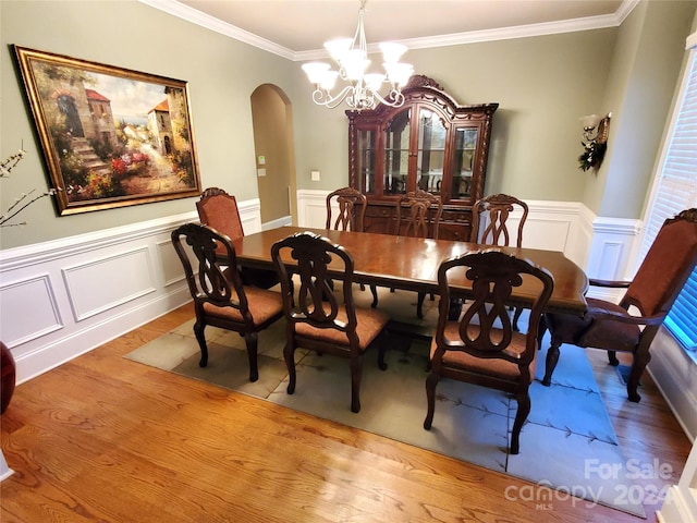 dining area featuring ornamental molding, light wood-type flooring, and a notable chandelier