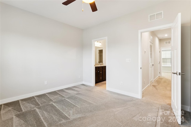 unfurnished bedroom with light colored carpet, ceiling fan, and connected bathroom