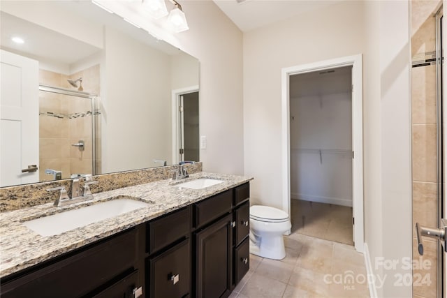 bathroom featuring tile patterned flooring, vanity, toilet, and a shower with shower door