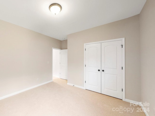 unfurnished bedroom with light carpet and a closet