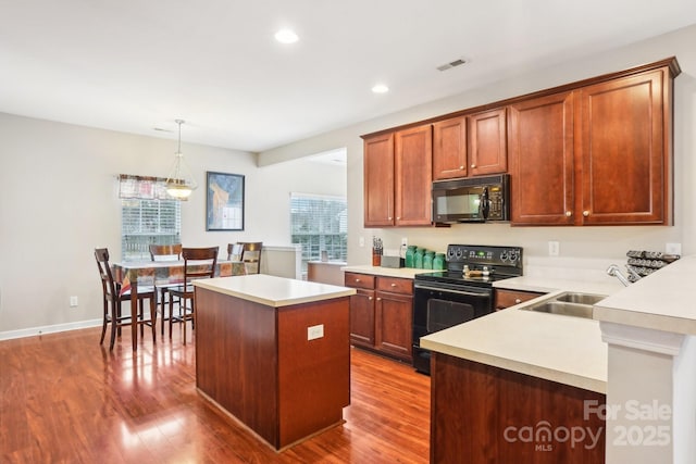 kitchen featuring a kitchen island, black appliances, a healthy amount of sunlight, and hanging light fixtures