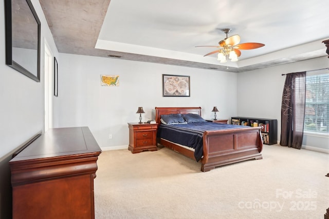 carpeted bedroom with ceiling fan and a raised ceiling