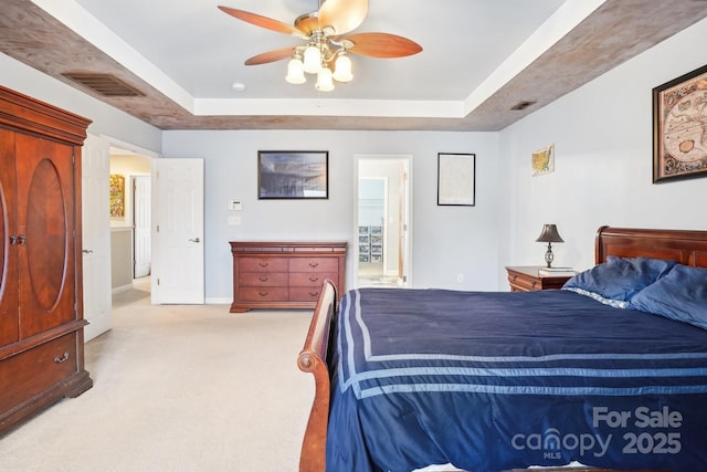 bedroom featuring light carpet, connected bathroom, ceiling fan, and a raised ceiling