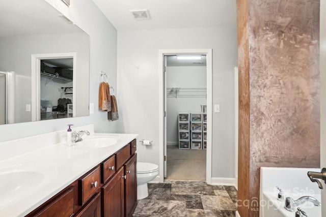 bathroom featuring toilet, vanity, and a tub to relax in