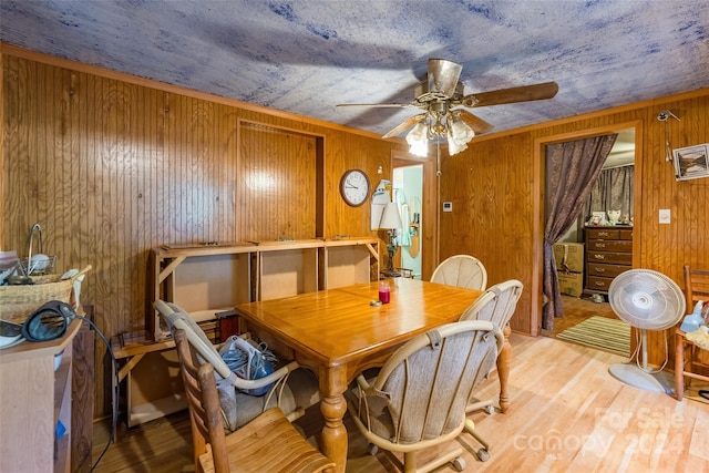 dining room with ceiling fan, wood walls, and light hardwood / wood-style floors