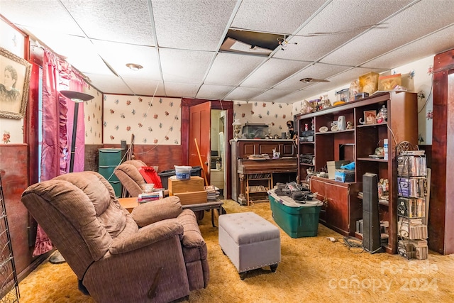 living area with a drop ceiling and carpet