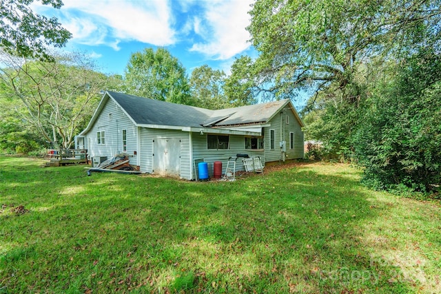 back of property with a deck and a yard