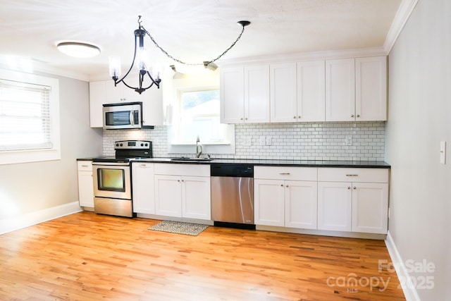 kitchen featuring stainless steel appliances, white cabinetry, and pendant lighting