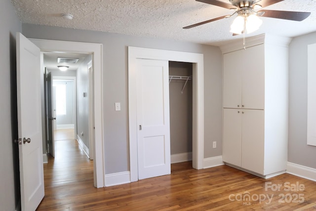 unfurnished bedroom with a textured ceiling, ceiling fan, and hardwood / wood-style floors